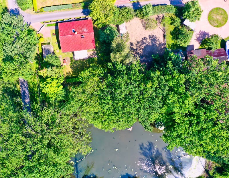 Gifhorn, Germany, July 3., 2019: Aerial view of a small cottage in the green next to a pond. Gifhorn, Germany, July 3., 2019: Aerial view of a small cottage in the green next to a pond