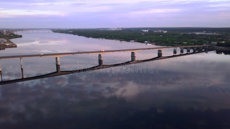 Widok z powietrza na długi most nad szeroką rzeką w zachodzie słońca. klip. obszar wiejski o spokojnej rzece w pobliżu wsi.