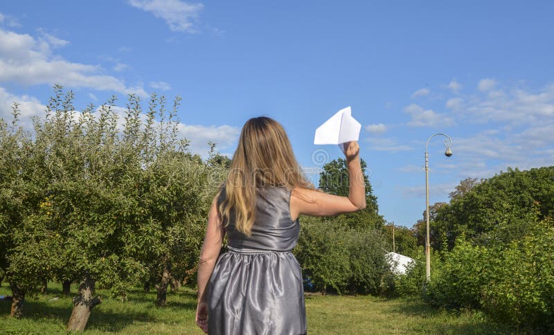 Widok z tyłu młodej kobiety w szarych sukienkach trzymającej w ręcznych papierowych samolotach przygotowany do rzucania. koncepcja nadziei i marzeń