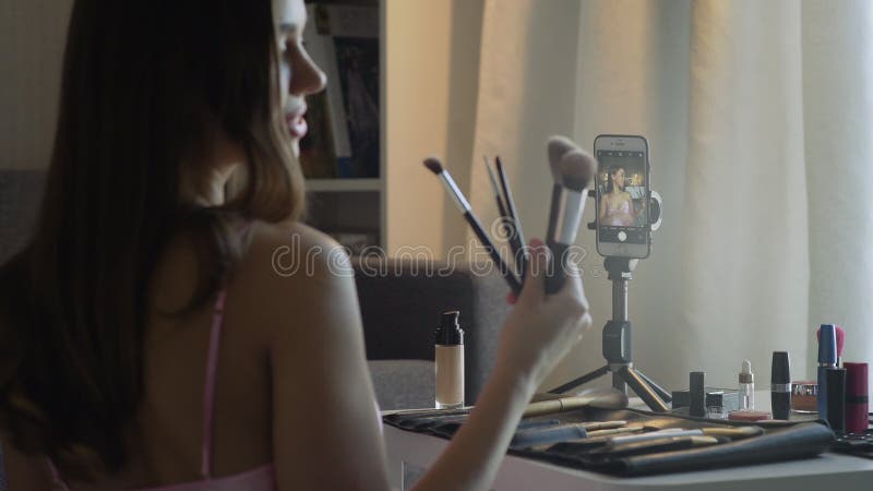 Widok z tyłu pięknej kobiety zabiera selfie z pędzlami na smartfonie zdjęcie wideo