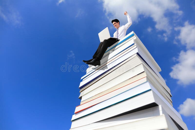 Knowledge is power - Happy business man using pc computer and sitting on a stack Of Books. Knowledge is power - Happy business man using pc computer and sitting on a stack Of Books