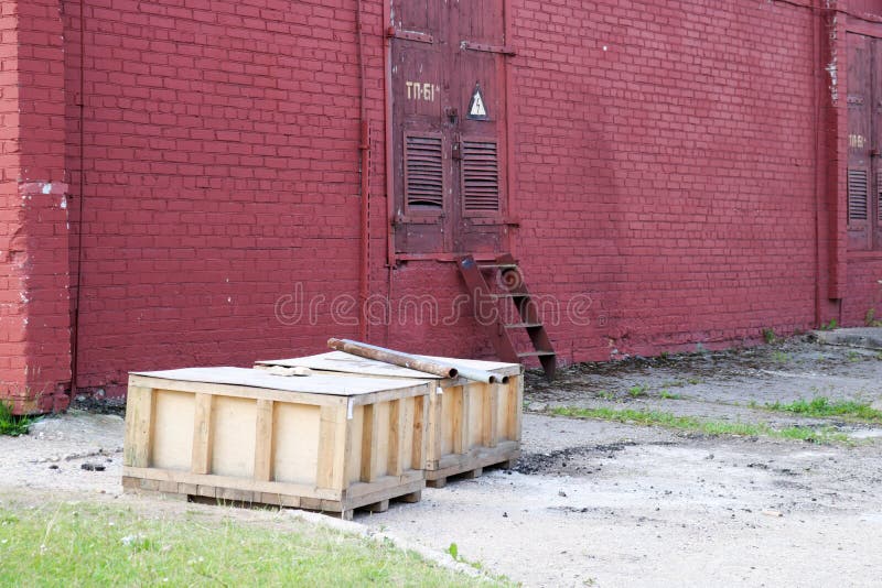 Wielcy drewniani pudełka z towary statywowym outside w na wolnym powietrzu w magazynie przemysłowy przedsięwzięcie przeciw czerwo fotografia stock Wielcy drewniani pudełka z towary statywowym outside w na wolnym powietrzu w magazynie przemysłowy przedsięwzięcie przeciw czerwo fotografia stock
