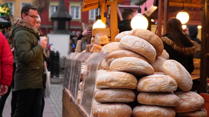 Wiele bochenków chleba jest sprzedawanych na rynku Ludzie wybierający produkty piekarnicze na targach świątecznych w wieczór zimo