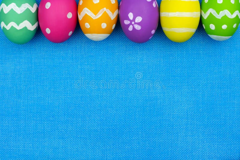 Colorful Easter egg top border over a blue burlap background. Colorful Easter egg top border over a blue burlap background