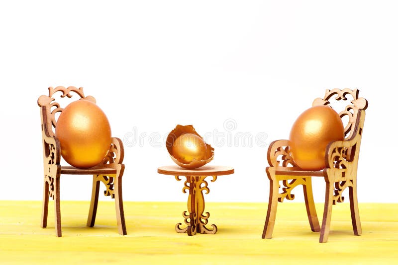 Happy easter egg. holiday bunny and eggs, spring flower backround golden eggs in broken shell, easter food painted in gold metallic color on wooden chair at table isolated on white background. Happy easter egg. holiday bunny and eggs, spring flower backround golden eggs in broken shell, easter food painted in gold metallic color on wooden chair at table isolated on white background