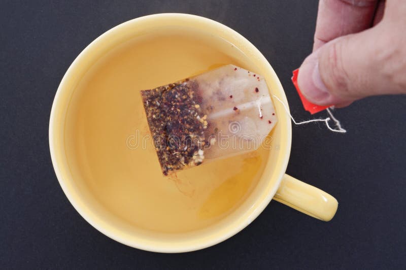 Large yellow mug with hand and teabag on black. Large yellow mug with hand and teabag on black