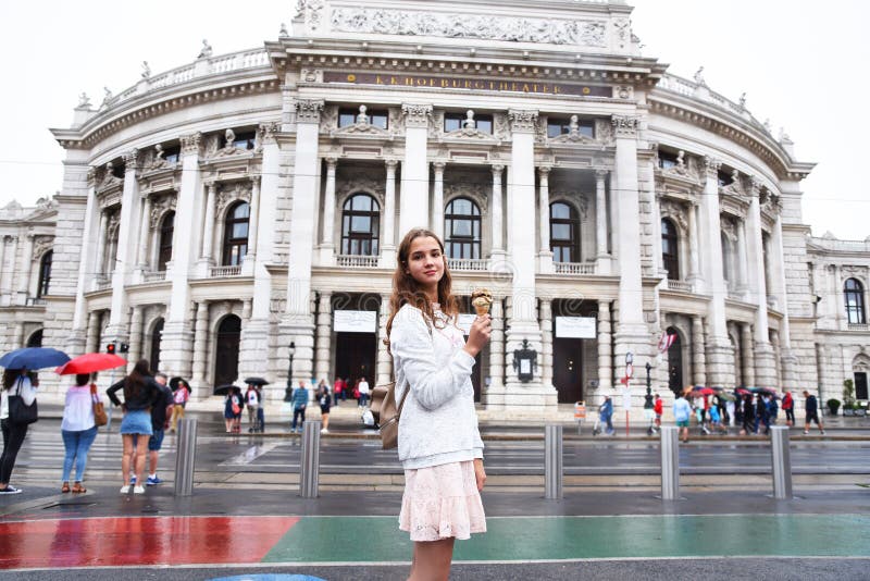 Wien p?st?r teatern Burgtheater, ?sterrike En flicka i en rosa kl?nning st?r p? bakgrunden av byggnaden royaltyfri bild Wien p?st?r teatern Burgtheater, ?sterrike En flicka i en rosa kl?nning st?r p? bakgrunden av byggnaden royaltyfri bild