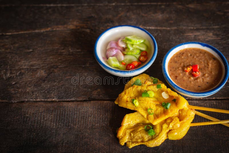 Wieprzowina satay z tajlandzkimi pikantno?? i arachidowym kumberlandem umieszczaj? cymi na drewno stole obraz royalty free