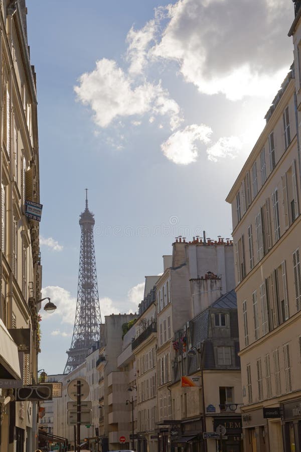 Paris - August 1, 2017: The Eiffel Tower visible in the distance from a Parisian street in the Summer of 2017. Paris - August 1, 2017: The Eiffel Tower visible in the distance from a Parisian street in the Summer of 2017.