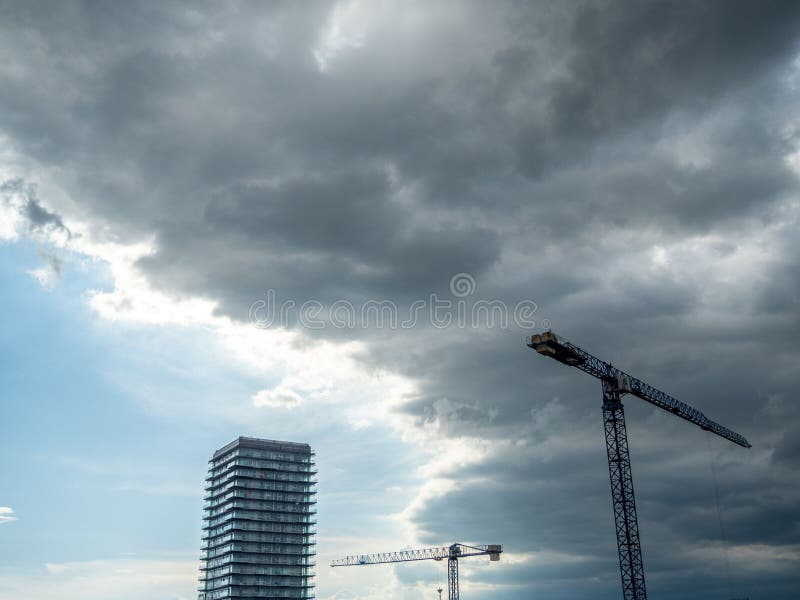 Wieżowiec i żurawie pod chmurnym niebem. fotografia royalty free