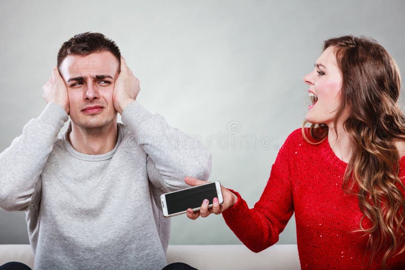 Angry furious wife shouting at husband showing text messages from lover mistress on his mobile phone. Outraged girlfriend find out about boyfriend affair romance betrayal. Cheating men covering ears. Angry furious wife shouting at husband showing text messages from lover mistress on his mobile phone. Outraged girlfriend find out about boyfriend affair romance betrayal. Cheating men covering ears.