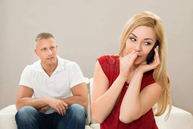 Wife Talking on Mobile Phone while Husband on Sofa Stoc photo