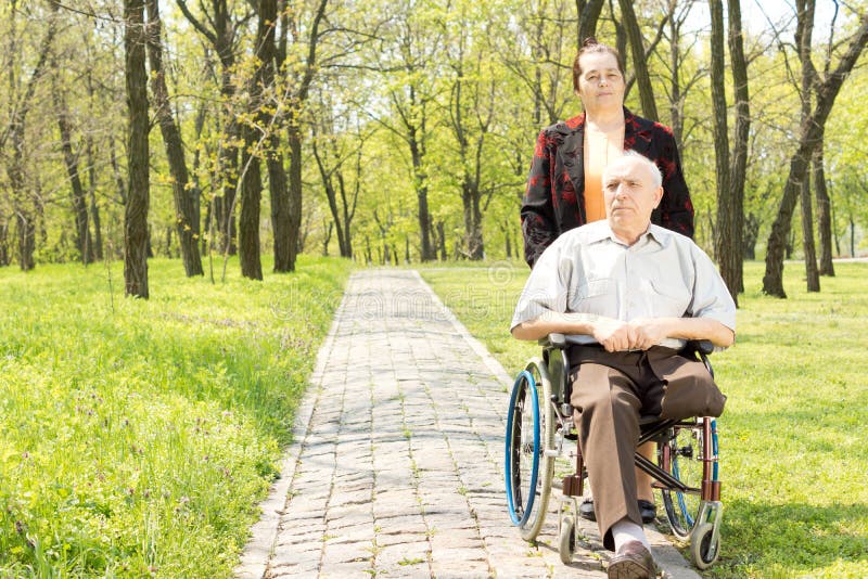 Wife walking a disabled man in a wheelchair