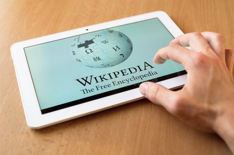 Man's hand use with his fingers tablet. Wikipedia app is on the screen. Wikipedia is popular free-access online encyclopedia