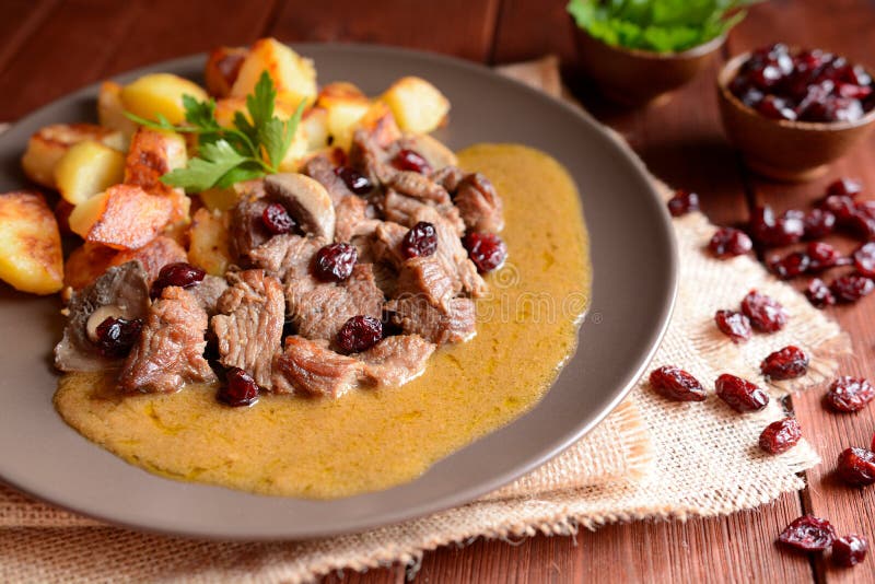 Wild boar meat with roasted potatoes, mushrooms and cranberries