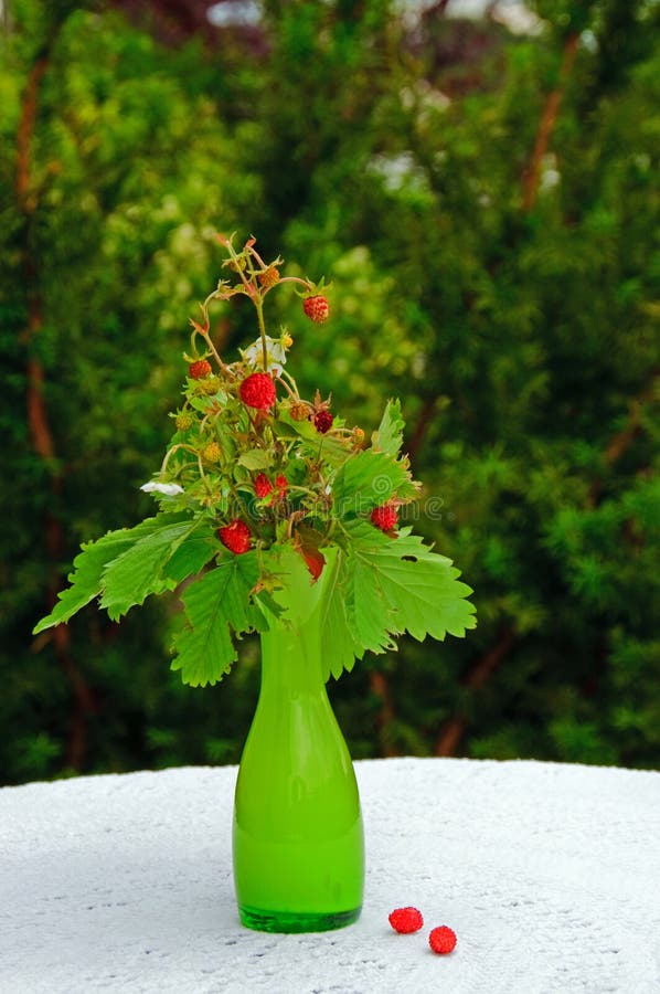 Some strawberries in av vase, standing on a table in a garden. Some strawberries in av vase, standing on a table in a garden.