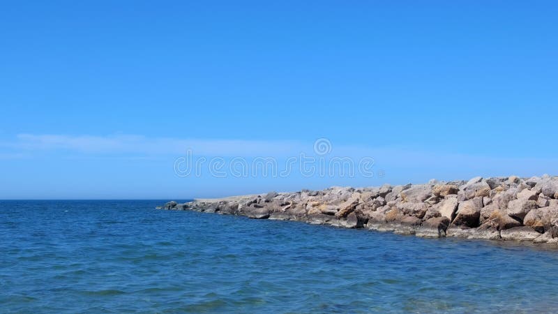 Nature seascape background wild sea shore with stones blue sky water sunny day.