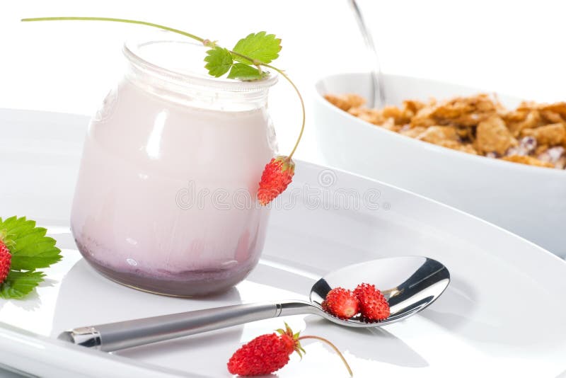 Jar of organic yogurt, delicious wild strawberries and bowl of oat flakes for breakfast over white background. Jar of organic yogurt, delicious wild strawberries and bowl of oat flakes for breakfast over white background