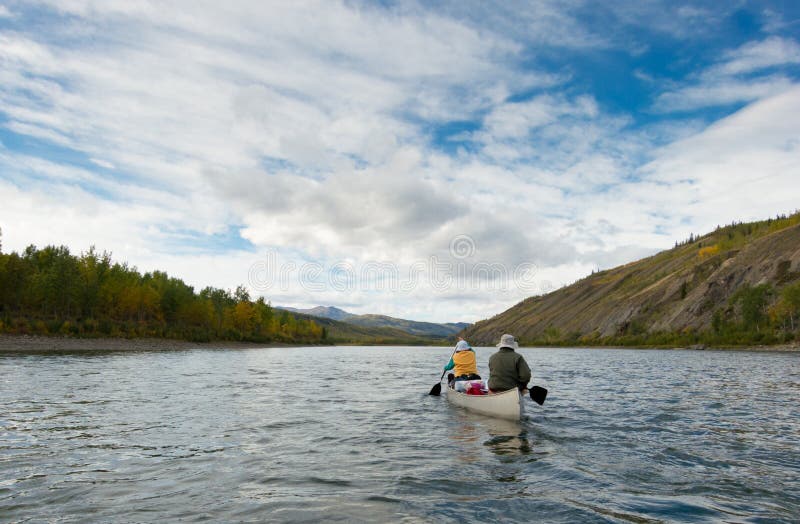A couple of canoeists on wilderness adventure trip paddling wide Pelly River, central Yukon Territory, Canada. A couple of canoeists on wilderness adventure trip paddling wide Pelly River, central Yukon Territory, Canada