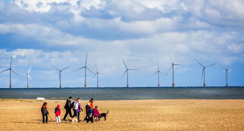 Wind farm off the coast of Yarmouth with family walking dogs on beach in Great Yarmouth, Norfolk, UK royalty free stock photos Wind farm off the coast of Yarmouth with family walking dogs on beach in Great Yarmouth, Norfolk, UK royalty free stock photos