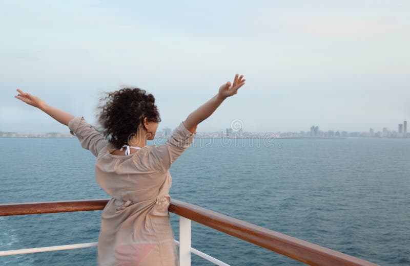 Wind in girl face. She standing on deck and watching the city at evening