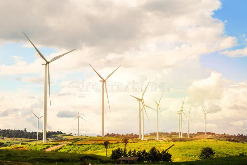 The wind turbine located at the top of the hill in summer and the blue sky and field in the foreground