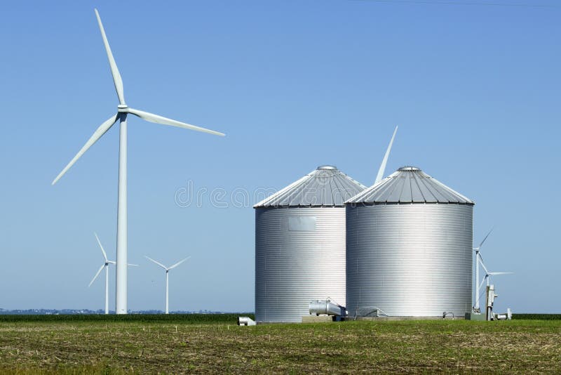 Two silos with wind turbines in surrounding fields. Two silos with wind turbines in surrounding fields.