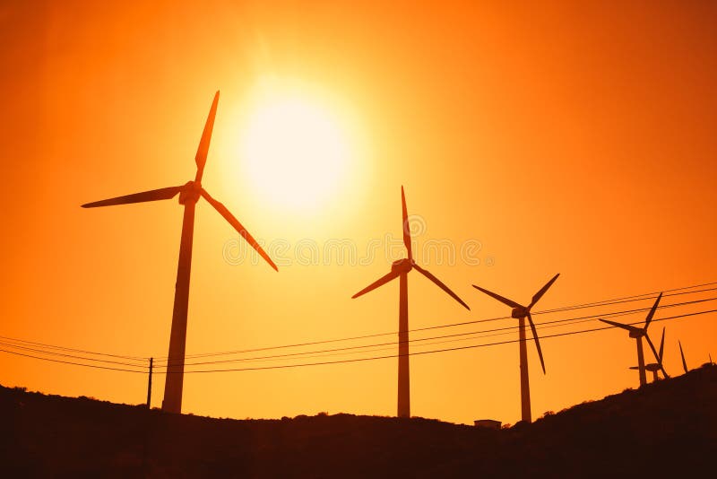 Wind turbines farm silhouettes on sun background