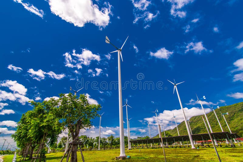 Wind turbines, solar energy in the middle of the plains, mountains on a bright blue day