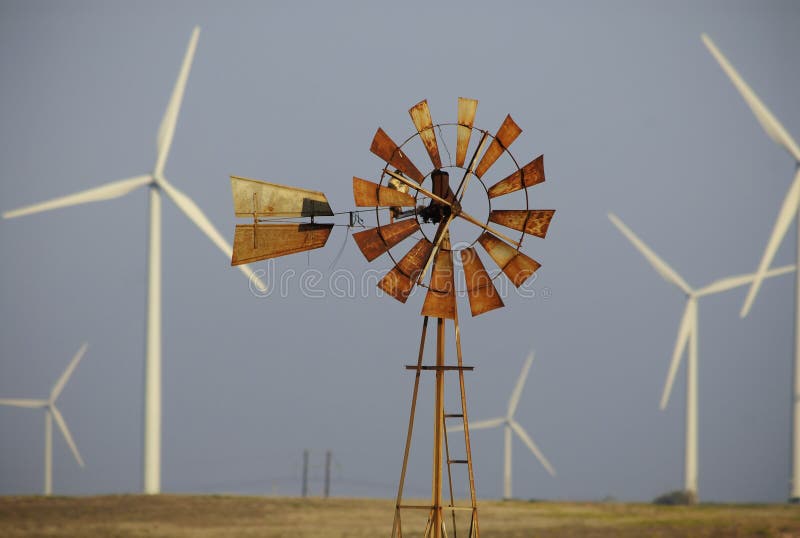 Old and new technologies stand in contrast as a farm windmill is surrounded by wind turbines. Old and new technologies stand in contrast as a farm windmill is surrounded by wind turbines.