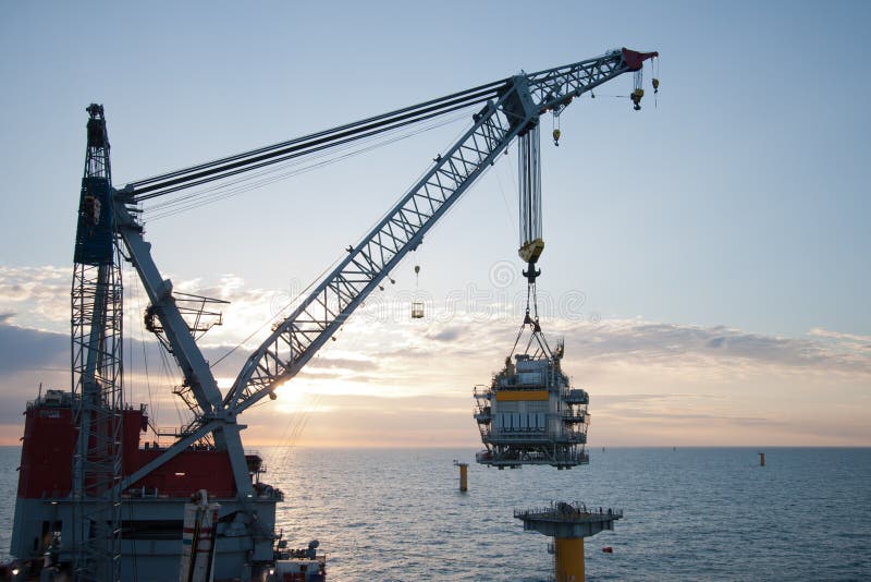 Large crane vessel installing a transformer platform in a windfarm under construction of the UK coast. Large crane vessel installing a transformer platform in a windfarm under construction of the UK coast