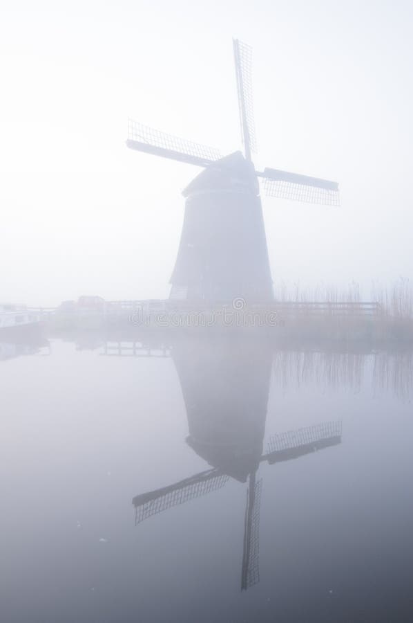 Windmolen en bezinning in mist bij dageraad, Nederland royalty-vrije stock afbeelding Windmolen en bezinning in mist bij dageraad, Nederland royalty-vrije stock afbeelding