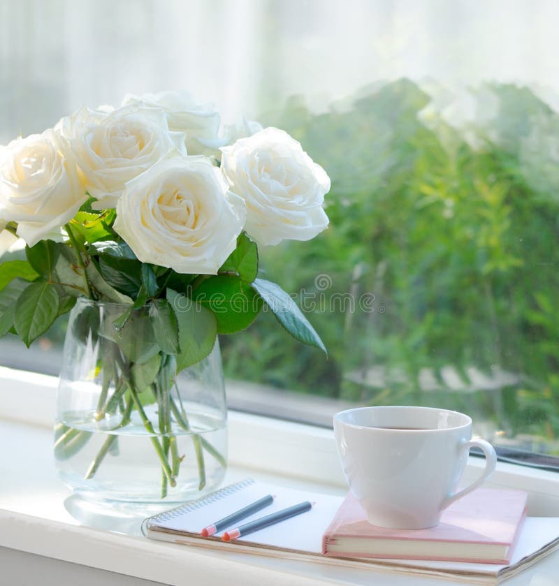 The window is beautifuller with beautiful white roses in a vase s nect to the window great way of home decoration