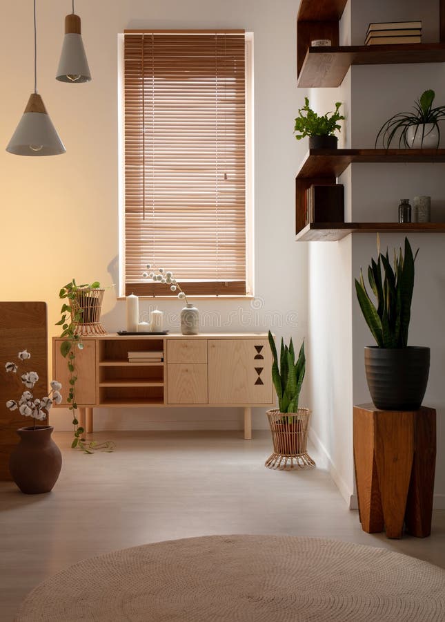 Window with blinds above wooden cupboard in bedroom interior with lamps and plants. Real photo royalty free stock images Window with blinds above wooden cupboard in bedroom interior with lamps and plants. Real photo royalty free stock images