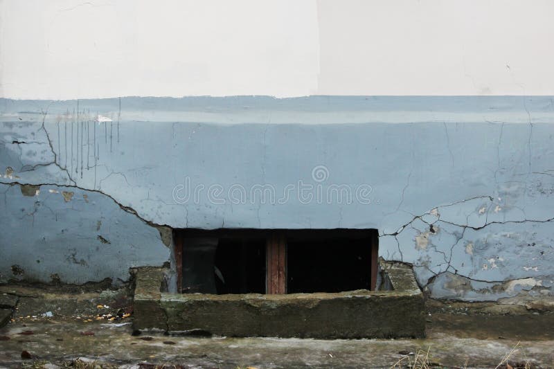 window with broken glass in a basement in an old house destroyed stucco gray and beige