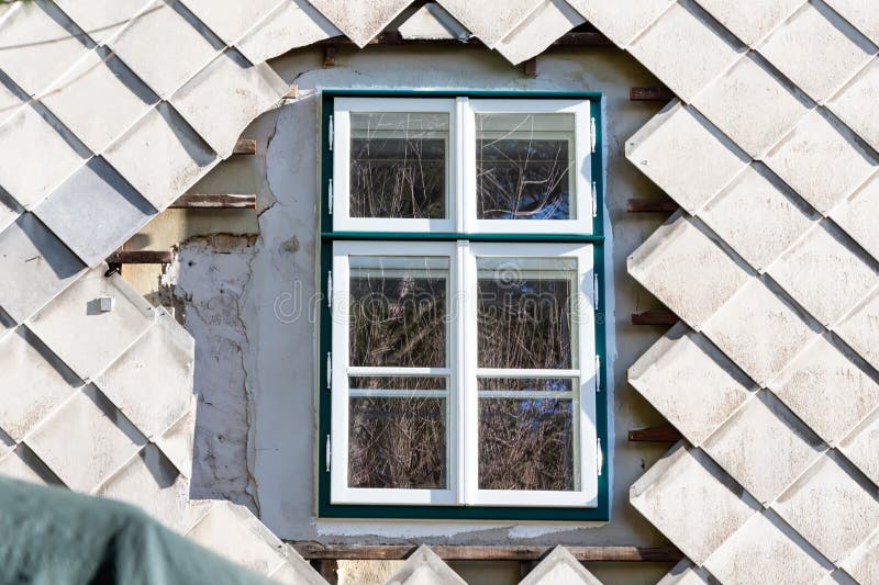 Window on a Building with the Diamondshaped Siding Falling Off. There is a Crack in the Wall