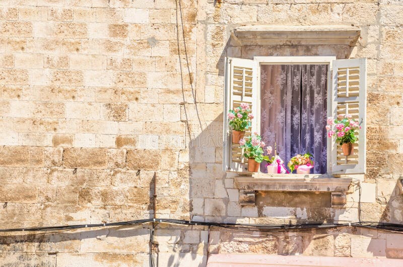 Window with flowers on the background of a white stone wall typical of architecture in Croatia royalty free stock photography Window with flowers on the background of a white stone wall typical of architecture in Croatia royalty free stock photography