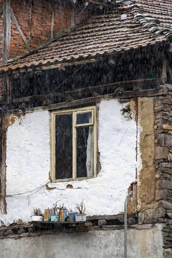Window of an old poor house with plant pots under the rain, village of Pirin in Pirin Mountains, Bulgaria, architectural detail royalty free stock photography Window of an old poor house with plant pots under the rain, village of Pirin in Pirin Mountains, Bulgaria, architectural detail royalty free stock photography