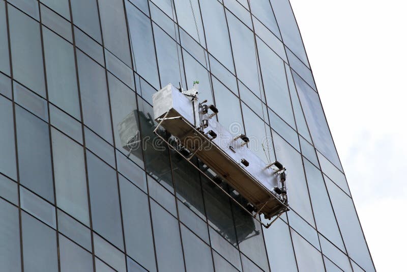 Window washing platform suspended on glass facade of a skyscraper