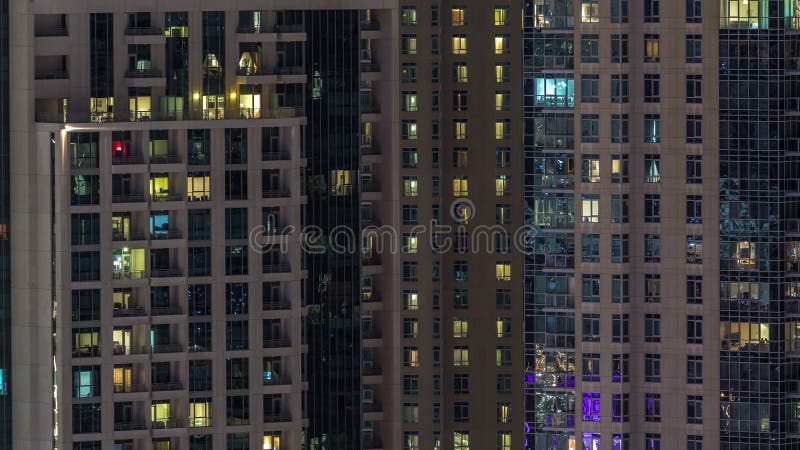 Windows del edificio de varios pisos con la iluminación dentro y de la gente de mudanza en timelapse de los apartamentos