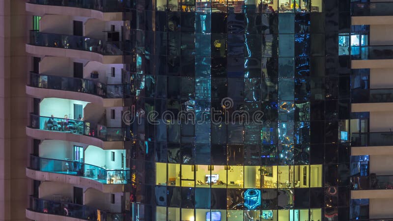 Windows del edificio de varios pisos de la gente interior y móvil de la iluminación de cristal y de acero dentro del timelapse