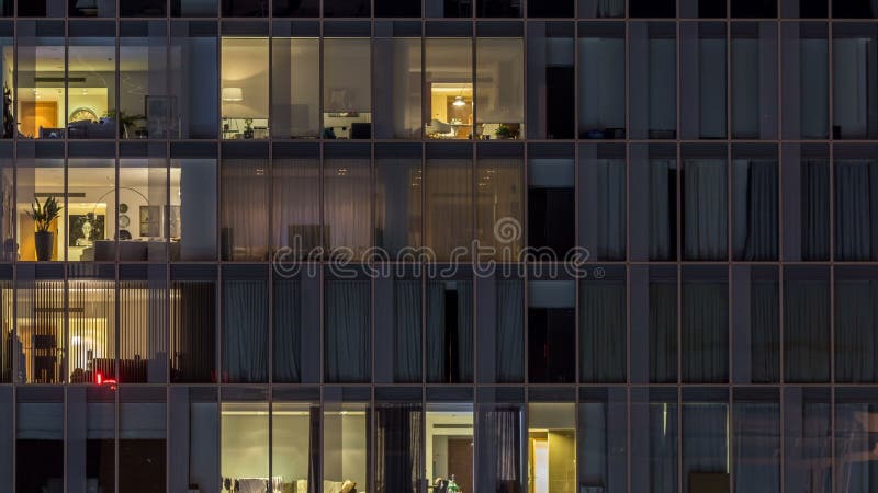 Windows del edificio de varios pisos de la gente interior y móvil de la iluminación de cristal y de acero dentro del timelapse