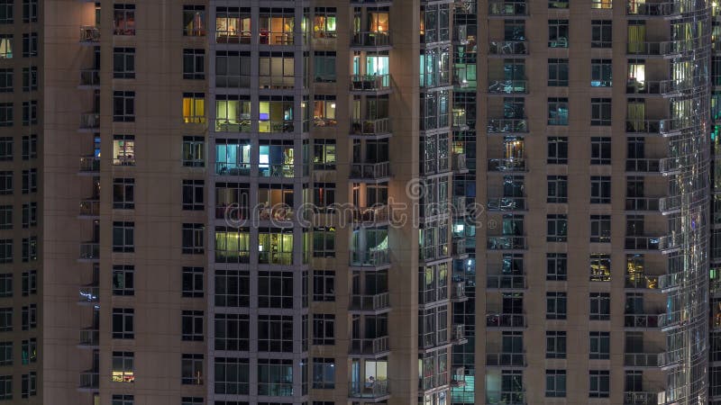 Windows du bâtiment à plusiers étages avec s'allumer à l'intérieur et des personnes en mouvement dans le timelapse d'appartements banque de vidéos