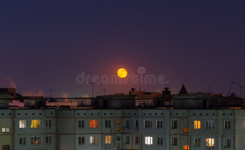 Windows, roofs and facade of an mass apartment buildings in Russia at full moon night.