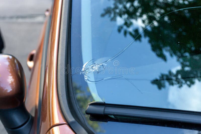 Broken car windshield glass from stone. Damaged windscreen on vehicle, close up. Broken car windshield glass from stone. Damaged windscreen on vehicle, close up