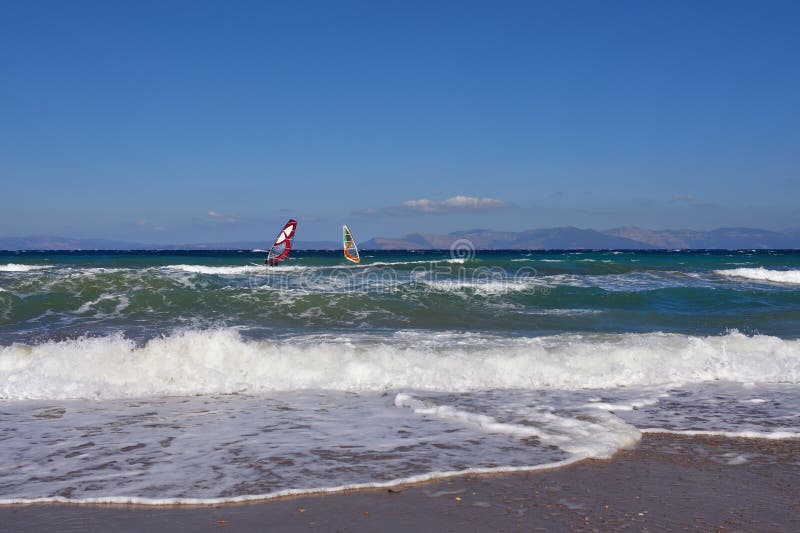 Beautiful view on the Aegean sea with two windsurfers from sandy beach in Artemis, Greece. Beautiful view on the Aegean sea with two windsurfers from sandy beach in Artemis, Greece
