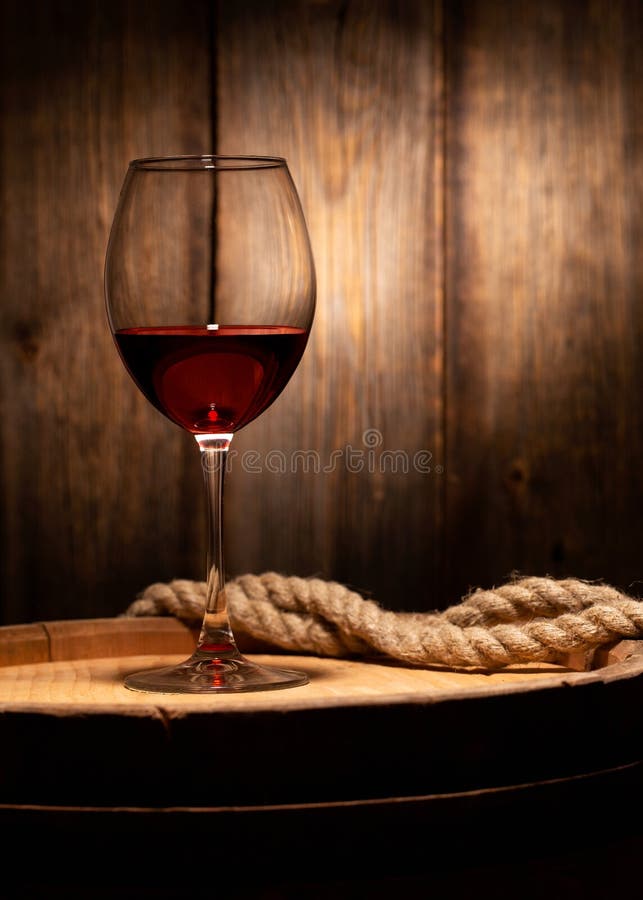 Still life with a glass of red wine. A glass of red wine standing on an old barrel against the background of a wooden wall, rope, vintage, alcohol, brown, beverage, dark, drink, cask, cellar, grape, bottle, keg, wineglass, agriculture, oak, winery, atmosphere, objects, storage, cool, vertical, nobody, cold, table, bordeaux, cabernet, selection, tasting, testing, basement, bow, bubble. Still life with a glass of red wine. A glass of red wine standing on an old barrel against the background of a wooden wall, rope, vintage, alcohol, brown, beverage, dark, drink, cask, cellar, grape, bottle, keg, wineglass, agriculture, oak, winery, atmosphere, objects, storage, cool, vertical, nobody, cold, table, bordeaux, cabernet, selection, tasting, testing, basement, bow, bubble