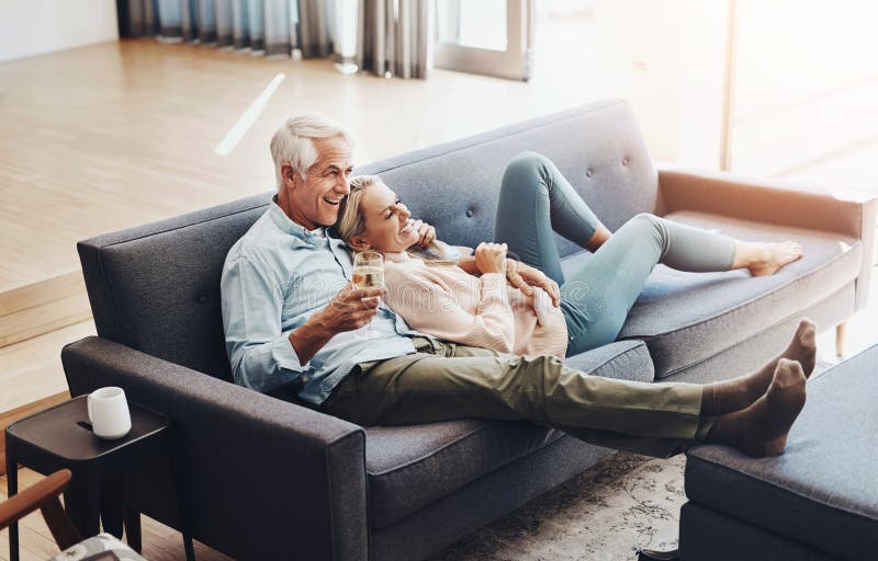 Wine, relax and mature couple on sofa watch movie on television together for at home date. Love, cuddle and senior man royalty free stock photos