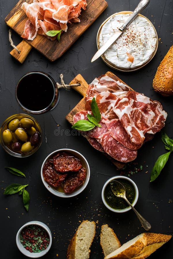 Wine snack set. Glass of red, meat selection, mediterranean olives, sun-dried tomatoes, baguette slices, camembert stock photography Wine snack set. Glass of red, meat selection, mediterranean olives, sun-dried tomatoes, baguette slices, camembert stock photography