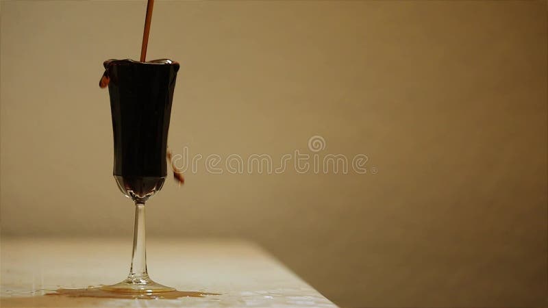 Wine spilled and overflowing into a glass cup.